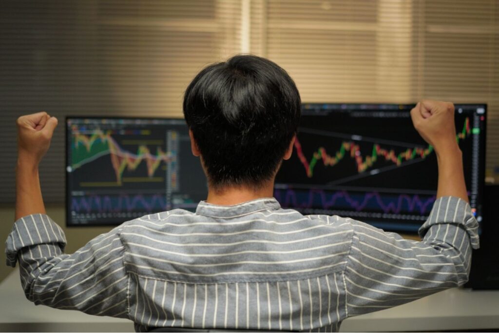 Trader reacting emotionally to stock market movements while watching trading screens